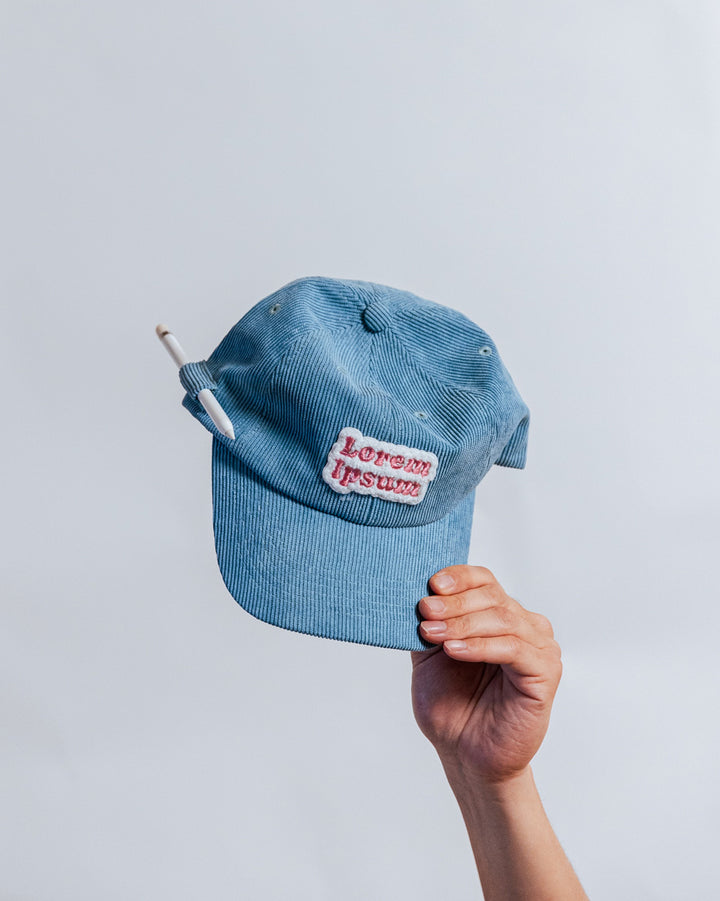 Blue corduroy dad hat with Lorem Ipsum puffy embroidery and pen holder